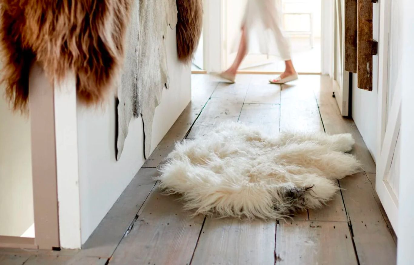 Une femme marche dans un couloir avec des tapis Dyreskinn.