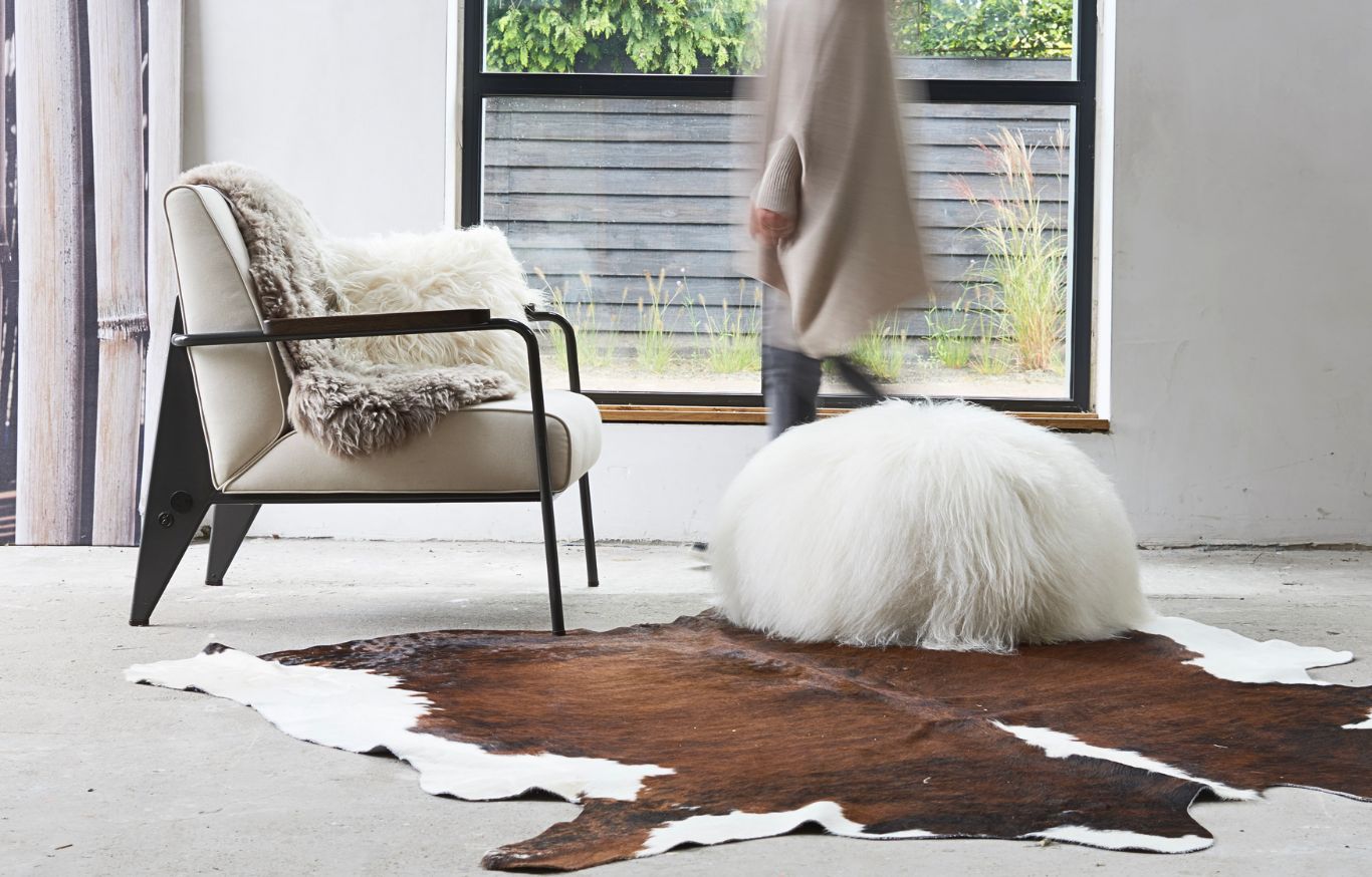 Un tapis en peau de vache Mouton dans une pièce avec une chaise.