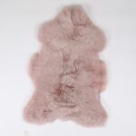 A Tapis peau de mouton rose bonbon | Tapis en peau de mouton 100×65 cm sur surface blanche.