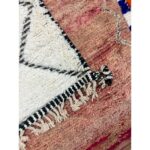 Un gros plan d'un Tapis Beni Ouarain beige | Tapis marocain de 160x104 cm, mettant en valeur ses franges et ses pompons.