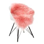A Tapis peau de mouton rose orange | Housse 100×65 cm sur chaise noire.