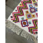 Un tapis berbère multicolore fait main avec des franges.