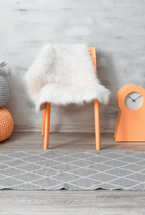 Une chaise avec des oreillers orange devant un mur.