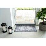 Un tapis porte d'entrée intérieure avec une bougie à côté d'une porte d'entrée.