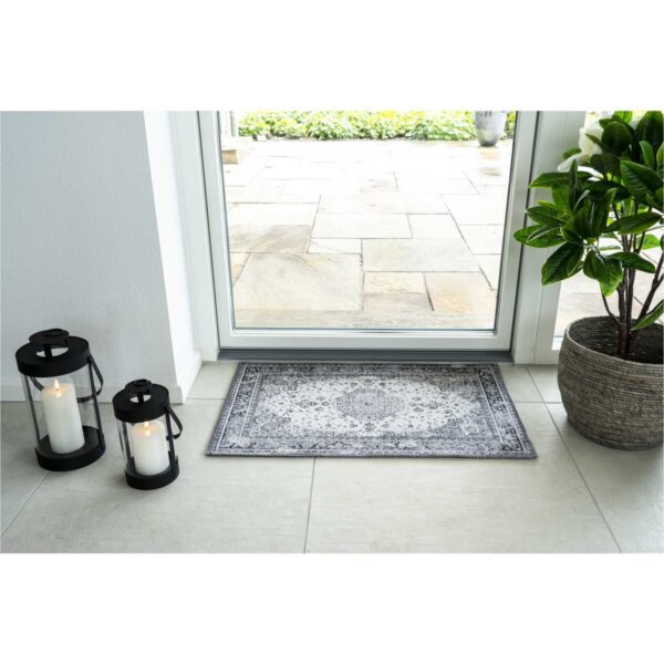 Un tapis porte d'entrée intérieure avec une bougie à côté d'une porte d'entrée.