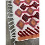 Un Tapis berbère coloré en laine colorée avec des franges et des pompons.