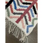 Un tapis berbère fait main moderne de 121x70 cm avec franges et pompons.