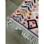 Un tapis berbère en laine colorée avec des franges sur le sol.