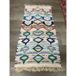 Un tapis berbère pure laine fait main de 125x63 cm, avec des franges sur le sol.