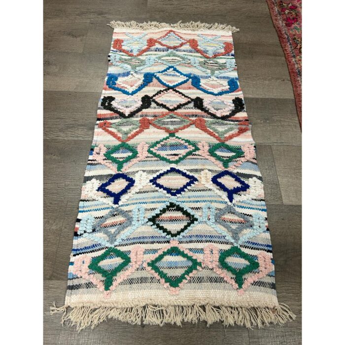 Un tapis berbère pure laine fait main de 125x63 cm, avec des franges sur le sol.
