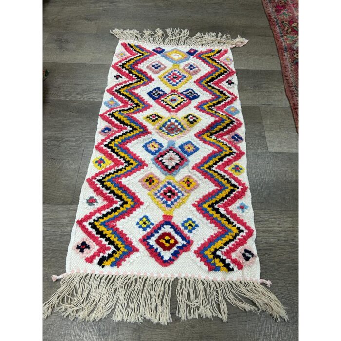 Un tapis berbère multicolore fait main avec des franges au sol. | 114x60cm