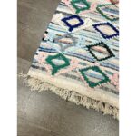 Un tapis berbère pure laine fait tapis principal, avec des franges au sol.