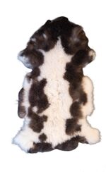 Un Tapis peau de mouton 100% naturel noir et blanc sur un fond blanc.