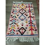 Un Tapis berbère laine colorée | 114x70 cm avec des franges sur le sol.