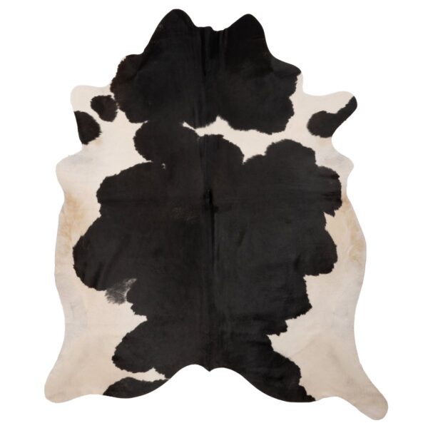 Un tapis peau de vache poils naturels noir et blanc sur un fond blanc.