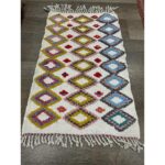 Un vibrant Tapis berbère en laine cousu à la main avec franges, mesurant 108x67 cm, orne le sol.