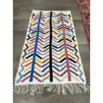Un tapis berbère fait main moderne | 121x70 cm coloré avec des franges sur le sol.