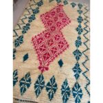 Un tapis berbère bleu et rose avec un motif géométrique de 250x150 cm.