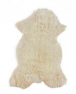 Un tapis peau de mouton blanc écru sur fond blanc.