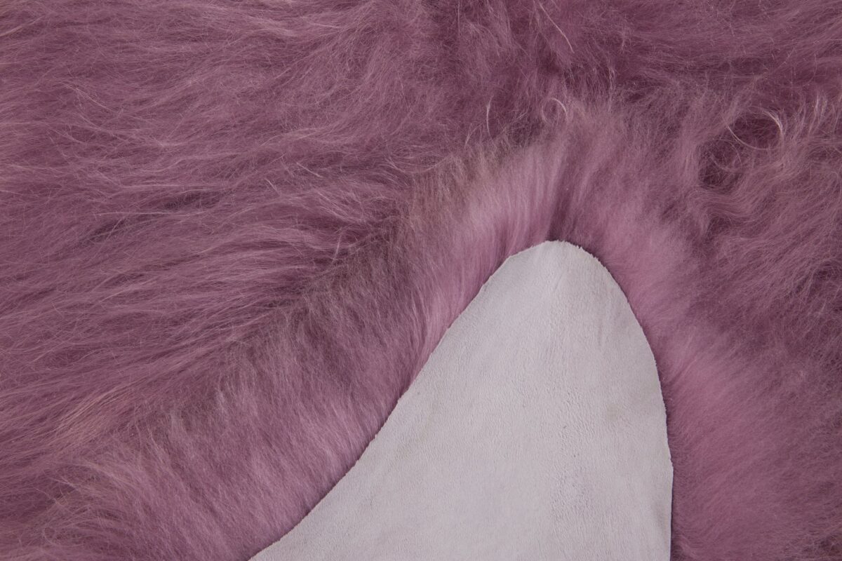 Un gros plan d'un Tapis peau de mouton rose foncé mesurant 100x65 cm.