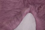 Un gros plan d'un Tapis peau de mouton rose foncé mesurant 100x65 cm.