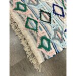 Un vibrant Tapis berbère pure laine fait main avec des franges, fait main en pure laine au sol.