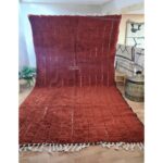 Un tapis marron chocolat poil long avec des franges sur le sol.