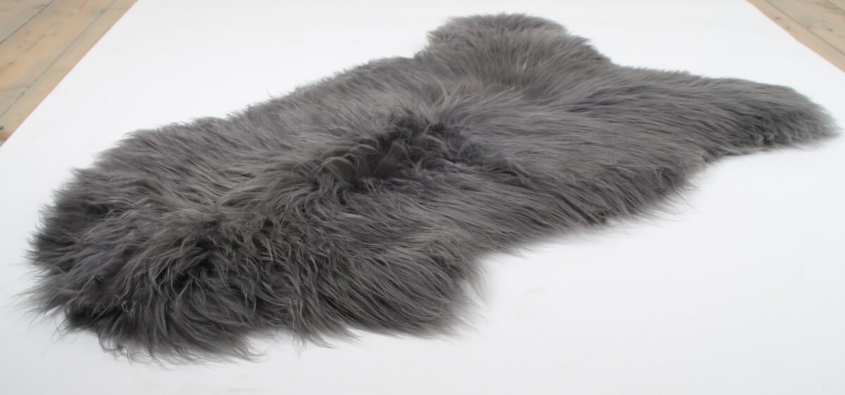 Un Tapis peau de mouton gris clair | 100×65 cm sur une surface blanche.