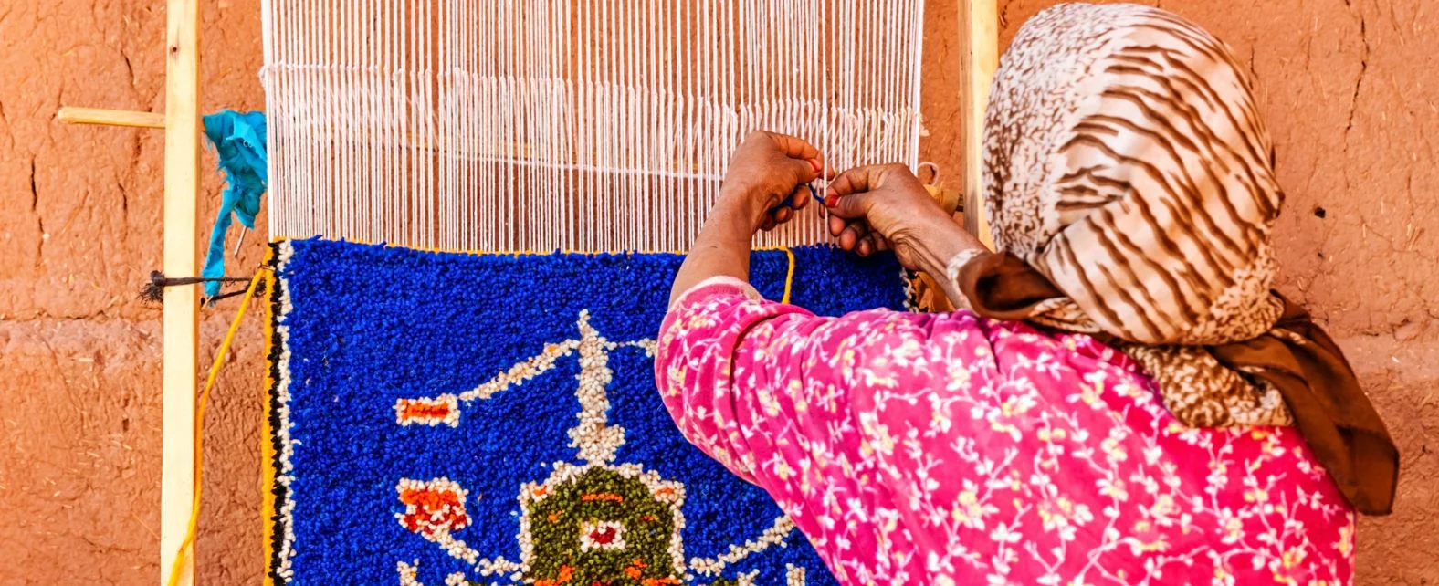 Femme marocaine en train de tisser et nouer à la main un tapis berbère