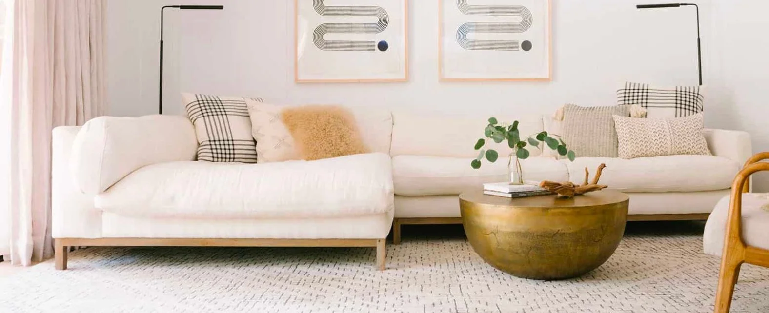 Salon moderne composé d’un canapé d’angle blanc et d’un tapis beige crème