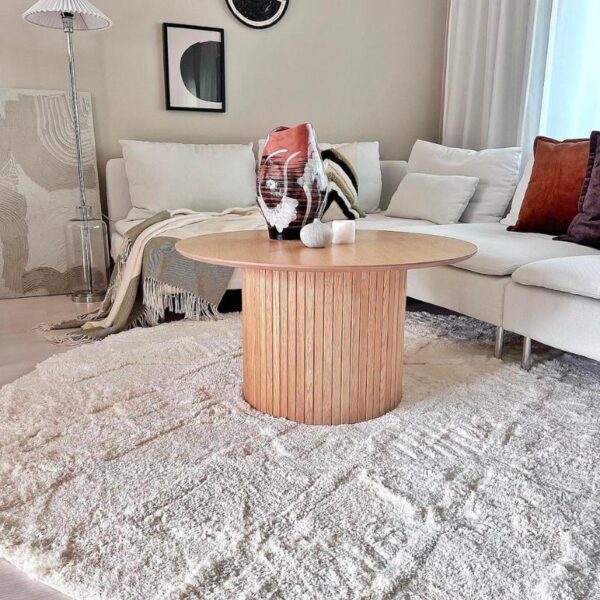 Tapis rond tufeté de couleur blanc devant un canapé d'angle