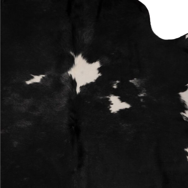 Tapis en peau de vache véritable blanc et noir, sur un fond blanc.