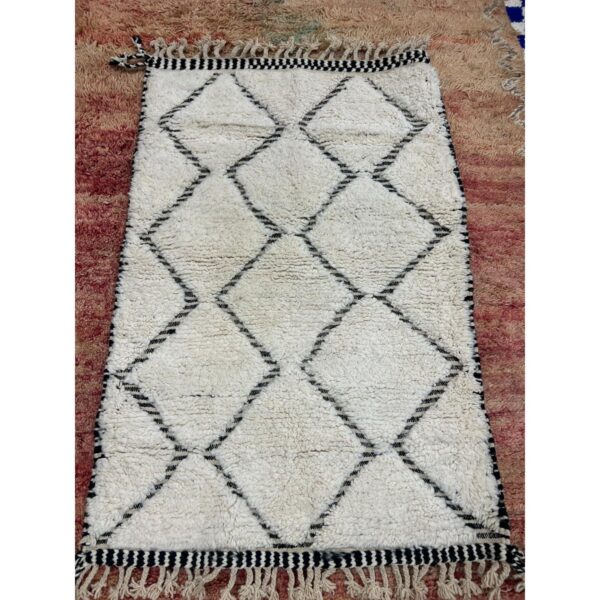 Un tapis Tapis Beni Ouarain noir et blanc, mesurant 160x104 cm, sur un Tapis Beni Ouarain beige | Tapis 160x104 cm.