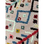 Un Tapis berbère laine coloré rose coloré orné de fleurs vibrantes, mesurant 114x70 cm.