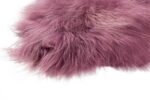 Un tapis peau de mouton rose foncé de 100×65 cm sur un fond blanc.