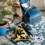 Un salon avec une chaise bleue et un tapis jaune.