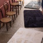 Une femme est assise sur un tapis dans une pièce.