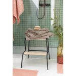 Un tabouret avec des serviettes et des plantes se trouve dans une salle de bain.