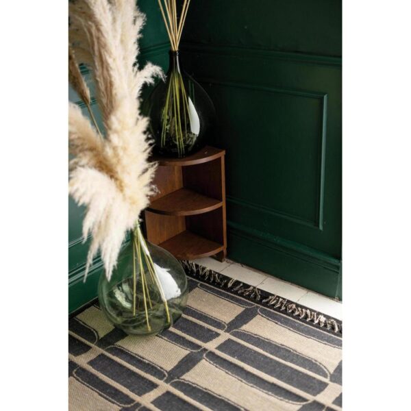 Une pièce avec un mur végétal et un vase d'herbes séchées.