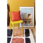 Une chaise jaune devant un tapis jaune.