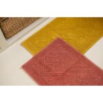 Un tapis de salle de bain jaune avec un panier dessus.