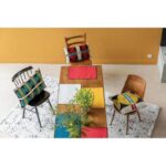 Une table à manger avec des chaises colorées et une nappe.