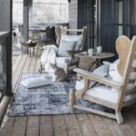 Un porche en bois avec des rocking-chairs et un chat.