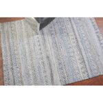 Un tapis rayé bleu et blanc sur un parquet.