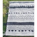 Un tapis noir et blanc avec des pompons.