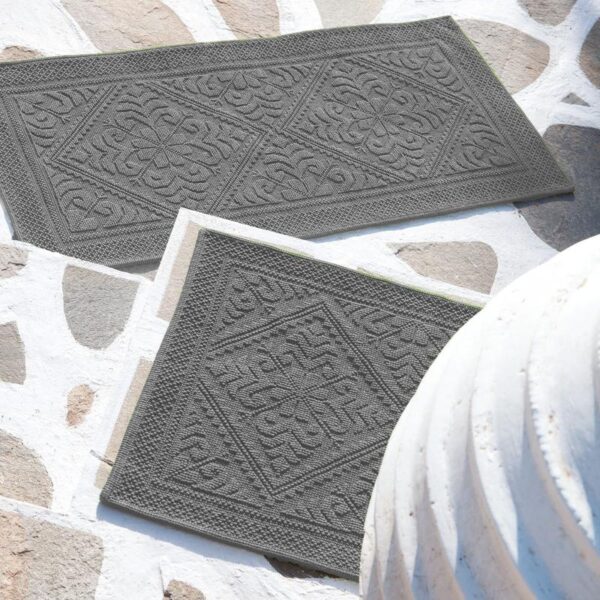 Une paire de paillassons gris sur un sol en pierre.