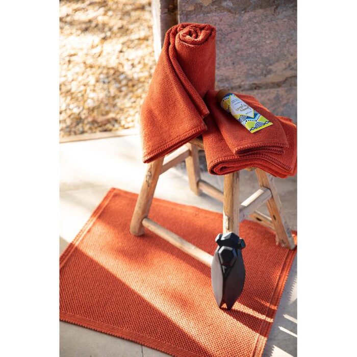 Un ensemble de serviettes à côté d’un tapis orange.