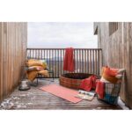 Une terrasse en bois avec des oreillers et des couvertures.