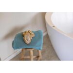 Une serviette bleue est posée sur un tabouret à côté d'une baignoire.