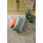 Deux oreillers sur un tapis à côté d'un vase.